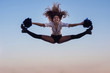 © Vladimir - Cheerleader girl with pompoms performs acrobatic element outdoors on the roof