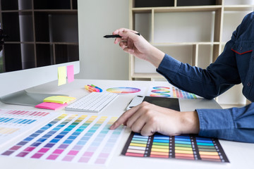 Poster - Male creative graphic designer working on color selection and color swatches, drawing on graphics tablet at workplace with work tools and accessories