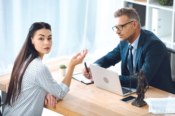 Wall Mural - lawyer taking notes and using laptop while client looking at camera