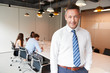 © Monkey Business - Portrait Of Mature Businessman Standing In Modern Boardroom With Colleagues Meeting Around Table In Background