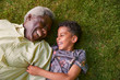 © Monkey Business - Boy and his granddad lying on grass, overhead close up