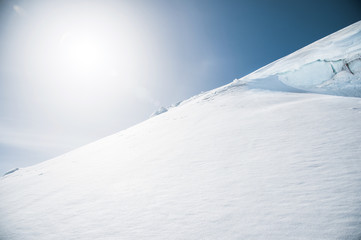 Sun over winter mountains covered with snow. Untouched freeride slope. Snow covered glacier