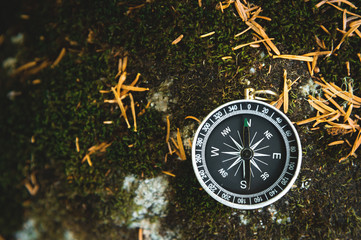 Magnetic compass with a black dial on a wild stone covered with green moss. The concept of finding the way and navigation