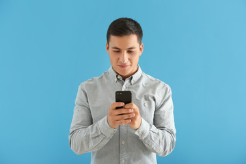 Wall Mural - young man with mobile phone on color background