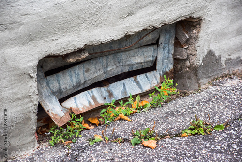 Fotografía Bent basement grating and crack in asphalt