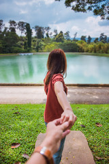 Traveling together. Follow me. Woman red hair in brown shirt  holding man by hand going to scenic view of beautiful nature.