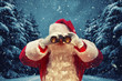 Santa Claus looking through binoculars. Christmas concept.