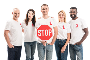 Wall Mural - group of people in blank white t-shirts with aids awareness red ribbons and stop road sign looking at camera isolated on white