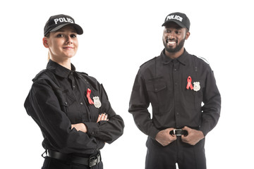 Wall Mural - smiling police officers with aids awareness red ribbons isolated on white