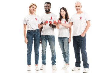 happy multiethnic people in blank white t-shirts with aids awareness red ribbons holding blocks with AIDS lettering isolated on white