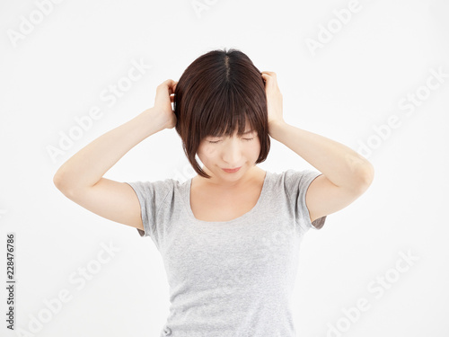 白背景で痛む頭を押さえる女性 Stock Photo Adobe Stock