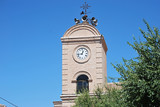 Fototapeta Paryż - Bell tower of the church with embedded clock dialing the hours