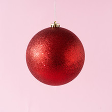 Red Glitter Christmas Bauble Decoration On Pastel Pink Background. New Year Party Background. Minimal Style.