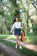 © soleg - young woman walking in the forest and playing guitar, summer nature, bright sunlight, shadows and green leaves, romantic feelings