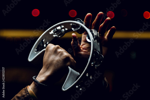 Cuadros en Lienzo Man playing the tambourine on the background of night lights