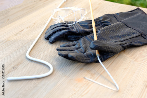 Fotografía Protective gloves, goggles and a hook for working with venomous snakes on the background of natural wood