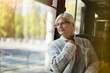 © pikselstock - Senior Woman Looking Through Window While Traveling In Bus