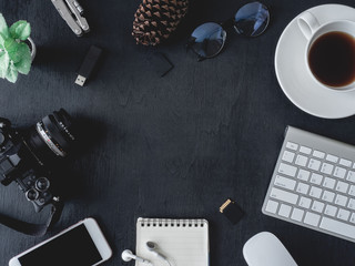 Wall Mural - top view office table concept with coffee cup, digital camera, notebook, glasses, laptop and smartphone on black table background.