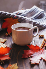 Fotomurales - Coffee mug with autumn maple leaves and women's woolen scarf on a wooden table