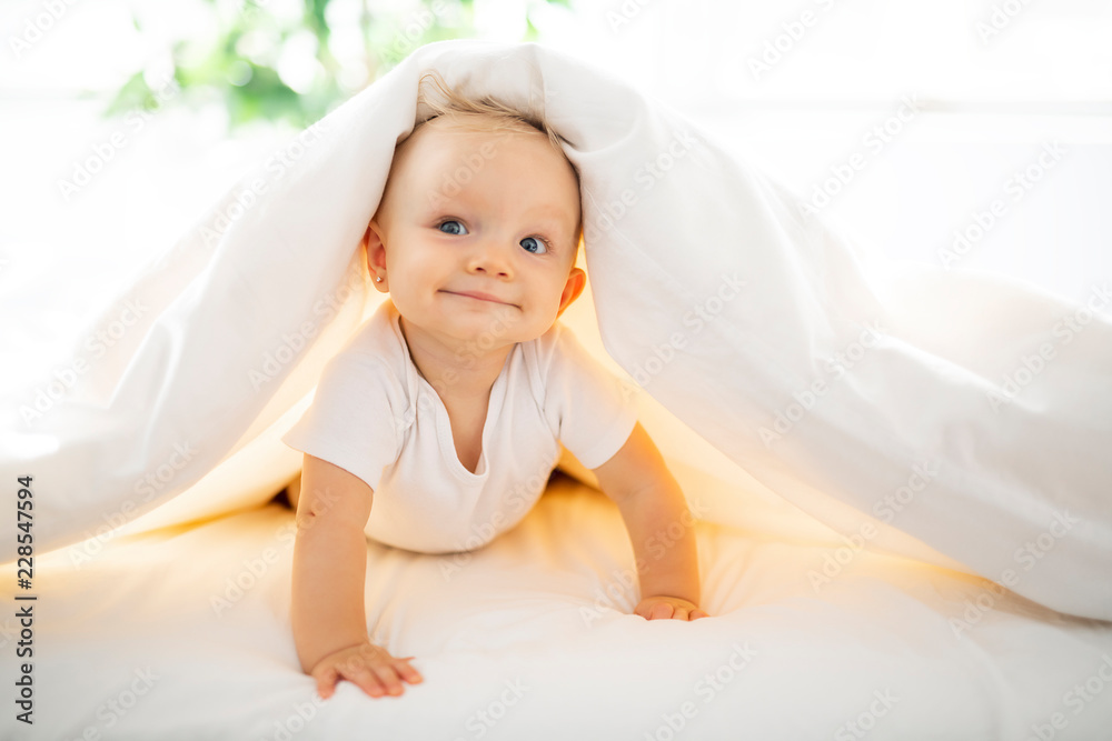 Cute baby girl lying on white sheet at home - obrazy, fototapety, plakaty 