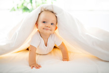 Cute Baby Girl Lying On White Sheet At Home