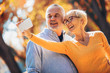 © Mediteraneo - Active seniors taking selfies of them having fun outside in the autumn forest