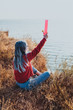 © Vaobullan - Rebel girl with blue hair in red sweater holding water bong near sea in sunrise