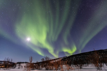 beautiful green northern lights and the moon in the blue sky