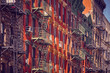 Old buildings with fire escapes at sunset, color toning applied, New York City, USA.