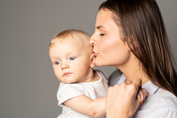 Wall Mural - A mother holdng his baby on studio gray background