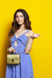 Young woman posing in blue sarafan on a yellow background.