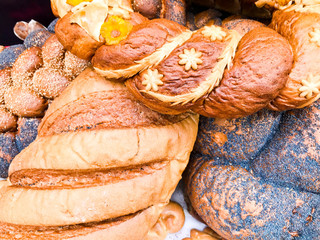 Wall Mural - Texture of ruddy brown wheat lush tasty white loaves, bread, black poppy buns. The background