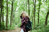 Fototapeta Las - Portrait of a young beautiful blond woman in tartan shirt holding a map in the forest.