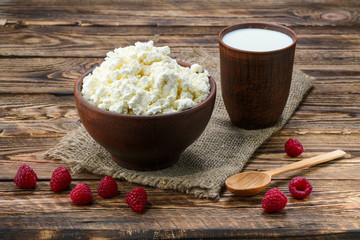 Wall Mural - Cottage cheese and milk in clayware on wooden table, sackcloth table-napkin and wooden spoon