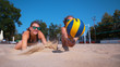 CLOSE UP: Female teammates both dive for ball during a beach volleyball game.