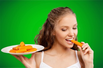 Wall Mural - Beautiful young woman eating a carrots