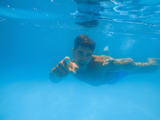 Wall Mural - Handsome young man swimming in pool, underwater view