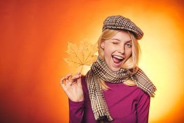 Happy young woman having fun with Leaf fall. Fashion portrait of beautiful sensual woman. Close-up portrait. Leaf fall. Attractive young woman in a seasonal clothes whith golden leaf.