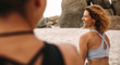 Leinwandbild Motiv Cheerful women in fitness wear sitting on the beach