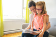 © Louis-Paul Photo - Mom with little girl reading book in sofa