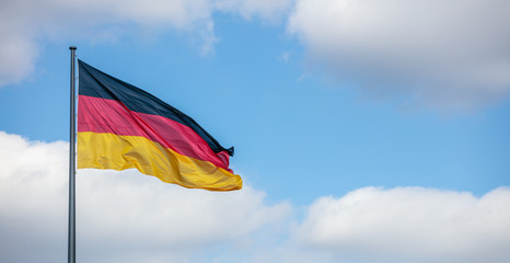 Wall Mural - German flag waving on flagpole. Cloudy blue sky background, copyspace, banner.