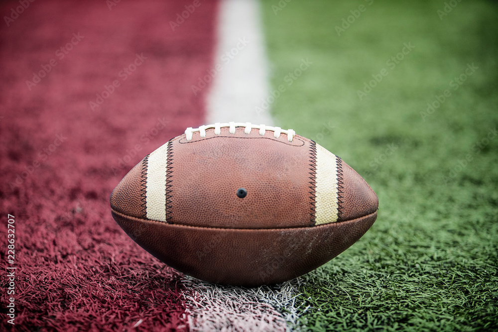 Closeup of an American Football resting on the goal line at a football stadium. Looks like its a touchdown. - obrazy, fototapety, plakaty 