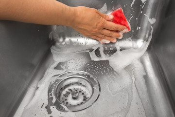 hand washes the sink with a sponge