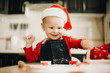© Strelciuc - Adorable infant boy in Santa hat playing with cutters