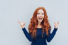 Excited Young Redhead Woman Pointing Upwards