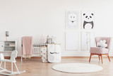 Stylish scandinavian nursery with white furniture and pink accents, cute poster on the white empty wall with copy space