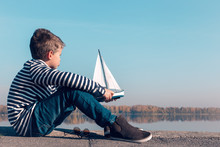 Child Playing With Sailing Boat In Beautiful Light