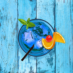 Poster - Blue lagoon cocktail with orange and maraschino cherry on vintage or grunge background