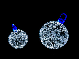 Two white Christmas ball of blurred bokeh lights on black background