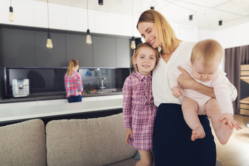 Wall Mural - Happy Mother Hugging Children Standing in Kitchen